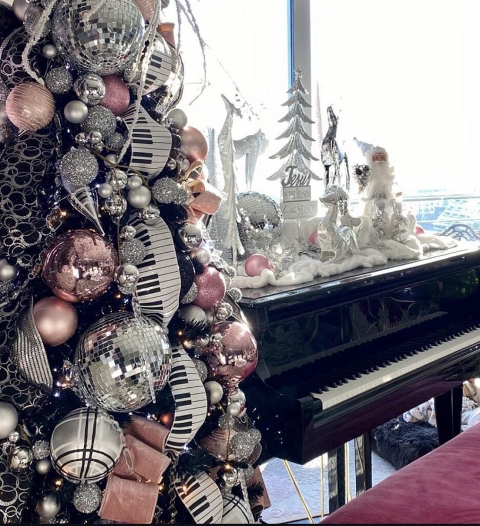 Playful pink-and-silver glam Christmas tree with disco-ball ornaments and piano-themed accents.