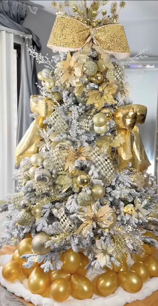 Flocked glam Christmas tree in gold with oversized bow, harlequin details, and dramatic balloon-style base décor.