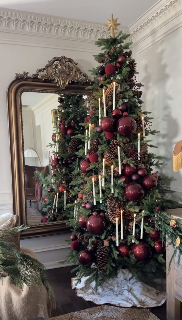 old-world candlelit tree with oversized burgundy baubles, realistic LED tapers, pinecone clusters, berry sprays, mirror backdrop