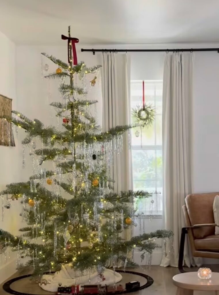sparse nordic tree with silver tinsel icicles and a red velvet bow, window wreath in bright natural light