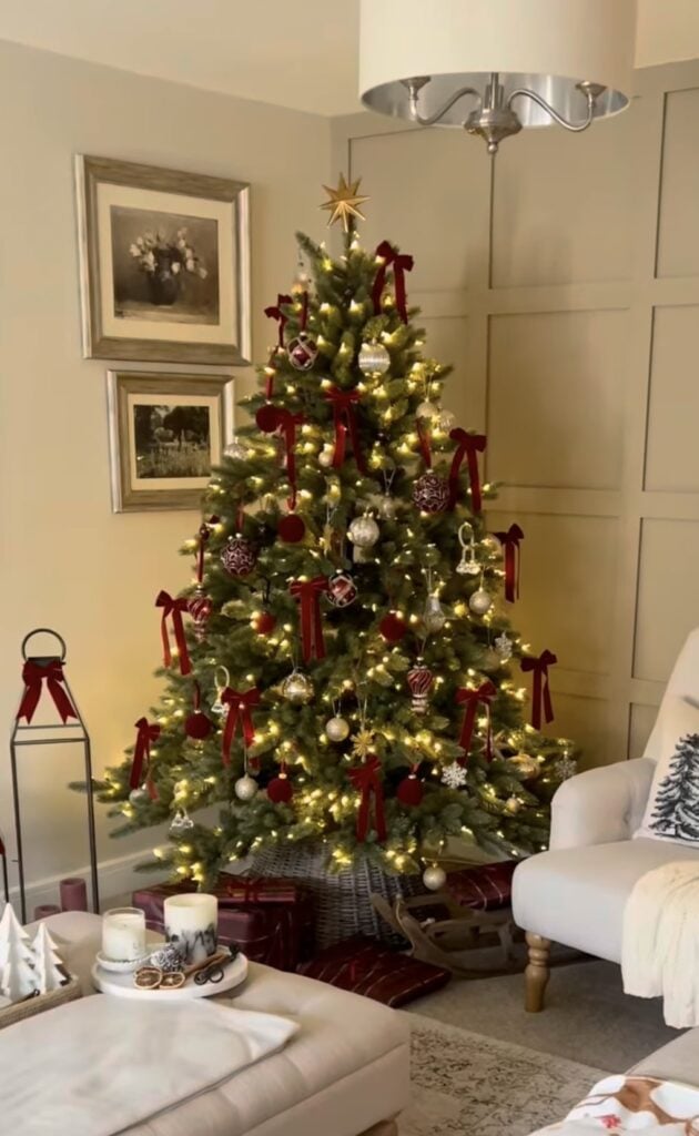 traditional evergreen with red velvet bows, silver and red ornaments, warm string lights, plaid wrapped gifts, gray woven collar