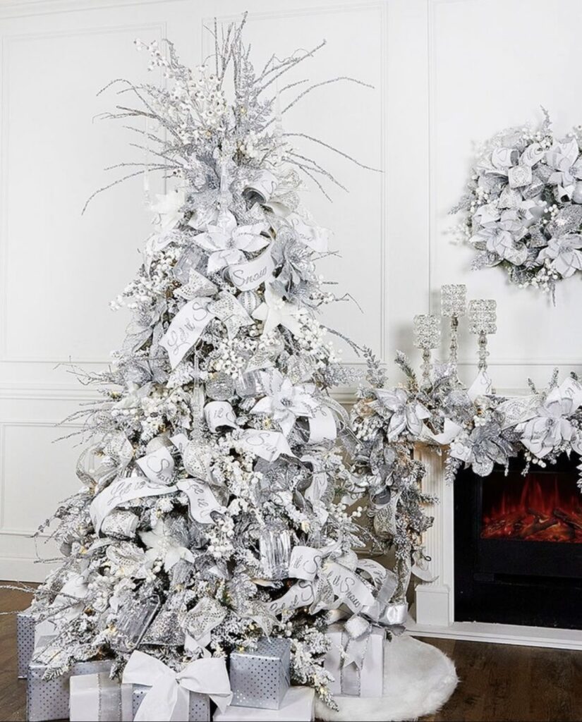 Winter wonderland Christmas mantel and tree with “Let it snow” ribbon, frosted branch sprays, white berry picks, crystal accents, and stacked gift boxes.