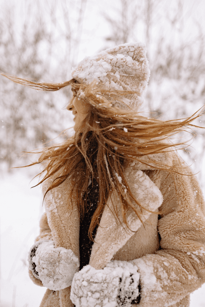 snowy woodland picture with woman in winter coat hat and mittens for winter solstice
