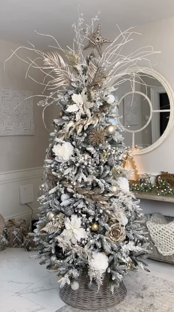 Christmas tree decorating in winter wonderland theme with white silver and gold in wicker basket base in  front of mirror 