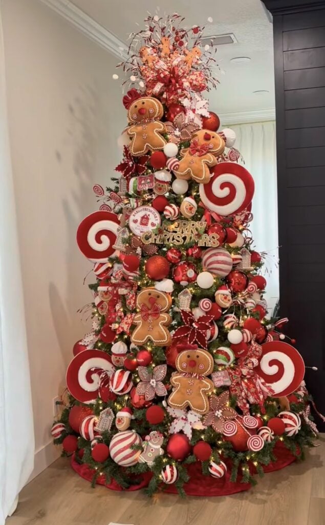 Bold red and white gingerbread Christmas tree with peppermint swirl ornaments, striped ribbon, and oversized candy accents.