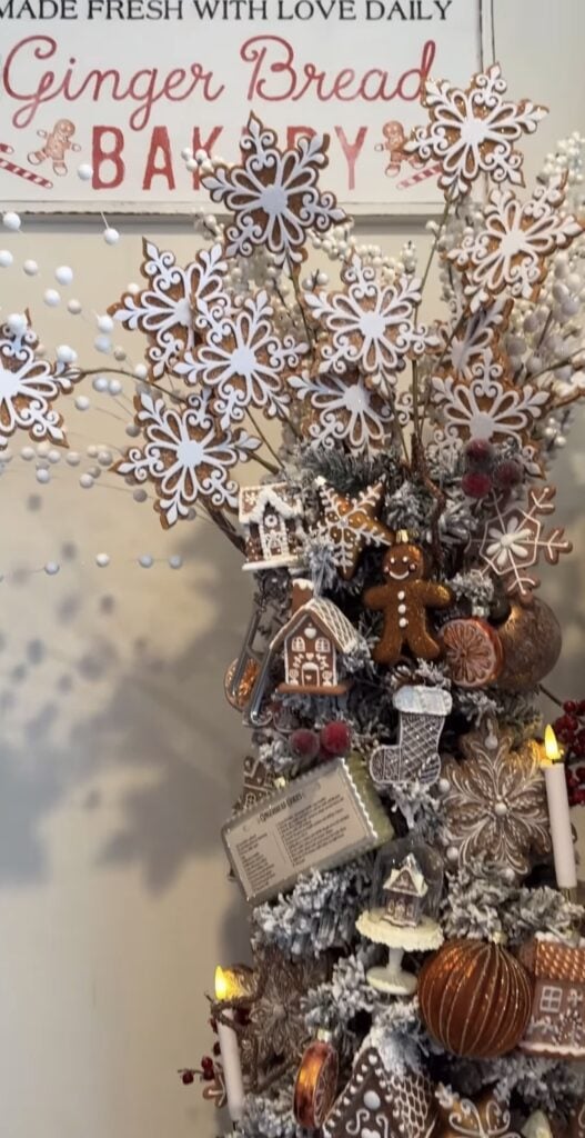 Neutral gingerbread Christmas tree with bakery signs, snowflake cookie sprays, and soft brown and white ornaments in a calm living room.