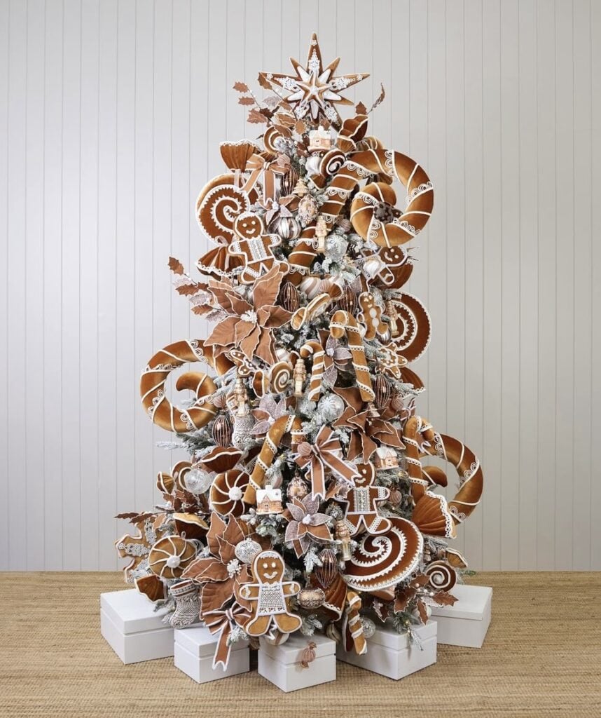 Neutral gingerbread Christmas tree with caramel and white cookie cutout ornaments, layered ribbon, and warm lights in a cozy living room.