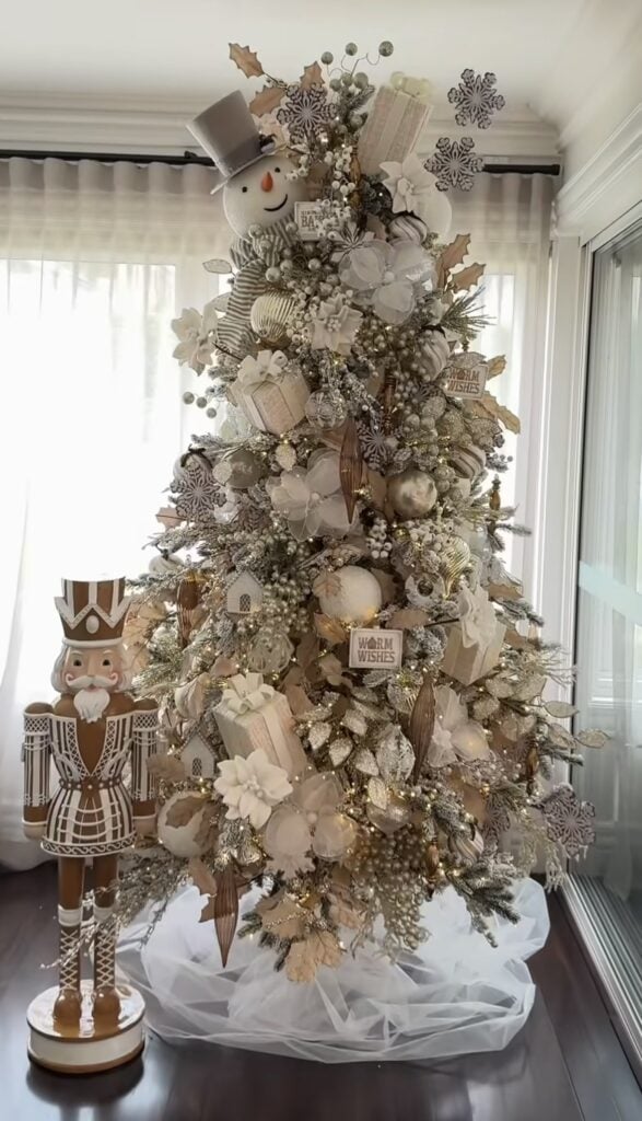 White and gold gingerbread-inspired Christmas tree with snowman topper, nutcracker figures, and soft cookie-style ornaments.