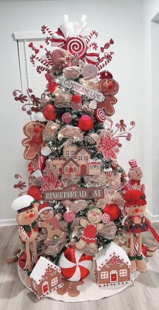 Red and white gingerbread street Christmas tree with candy cane garlands, cookie house ornaments, and bold striped ribbon.