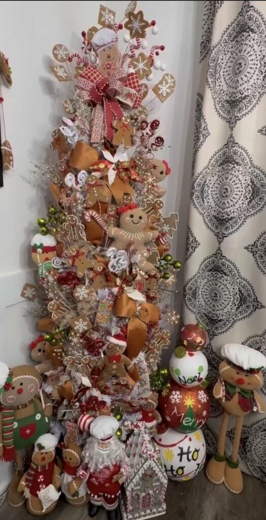 Tall skinny gingerbread baker-themed Christmas tree decorated with plush cookie characters, rolling pins, and candy accents.