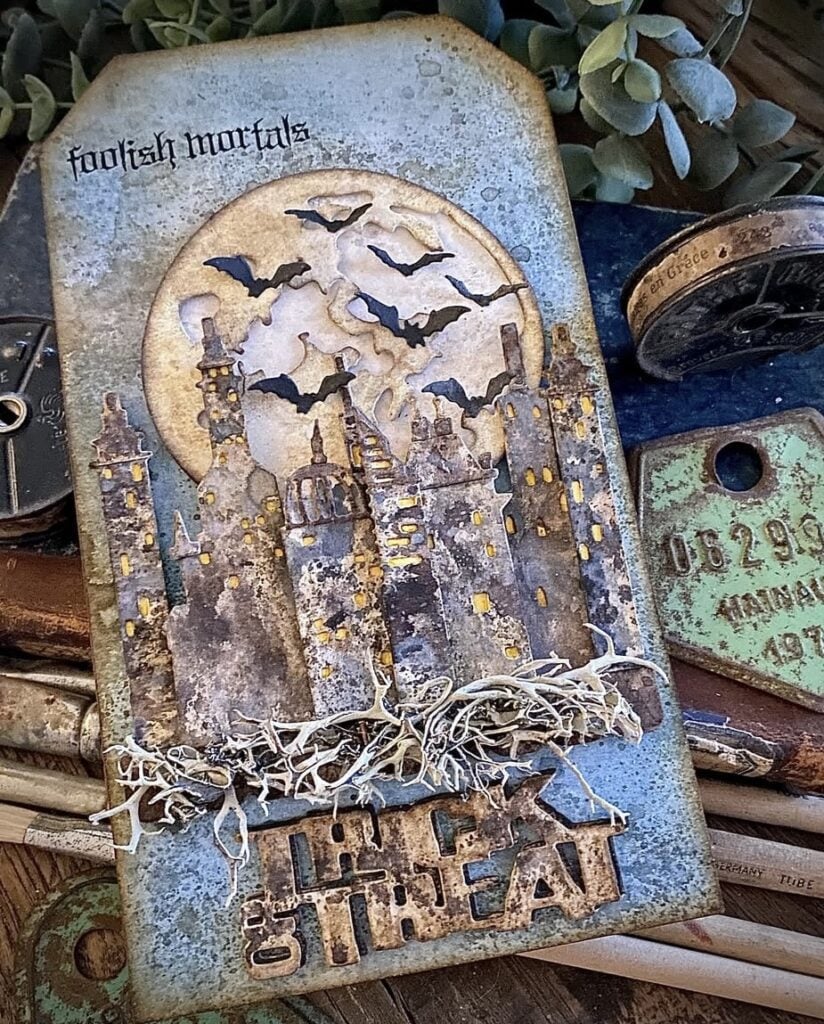 Mixed-media tag layout with haunted castle, full moon, bats, and layered papers in black and gray