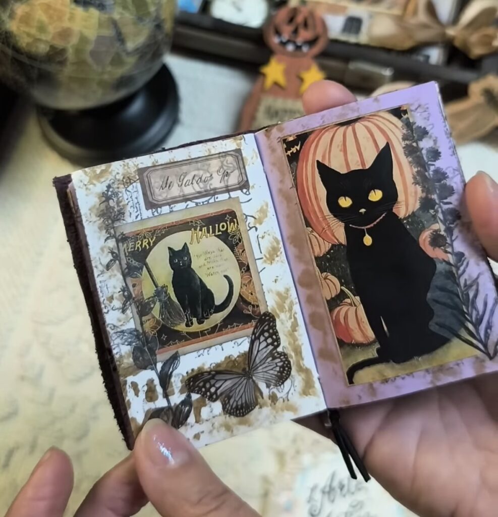 Mini book Halloween project with black cat and pumpkin die cuts, layered tabs, and ribbon.