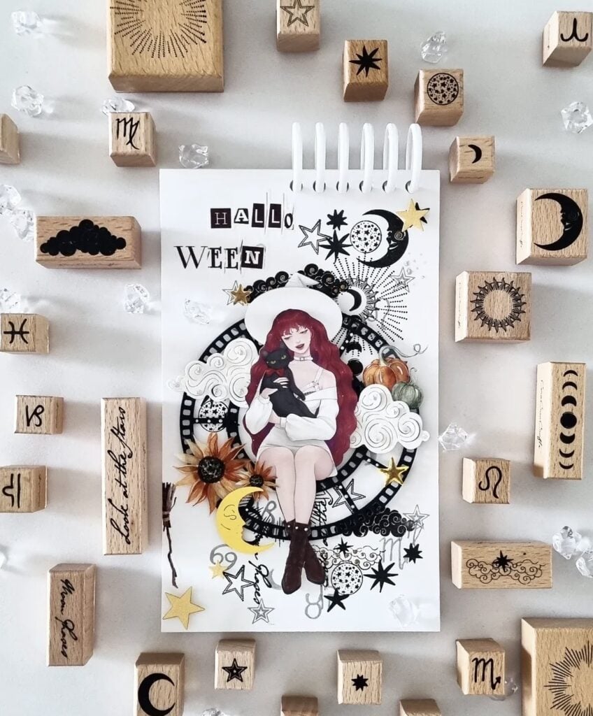 Redhead witch scrapbook page with black cat, celestial stamps, sunflowers, moons, and stars for a magical mixed media look.