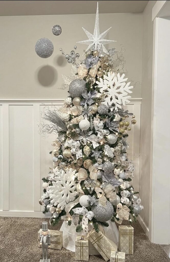 Winter wonderland Christmas tree with oversized snowflakes, giant baubles, mixed metallic ribbon, and a star topper.