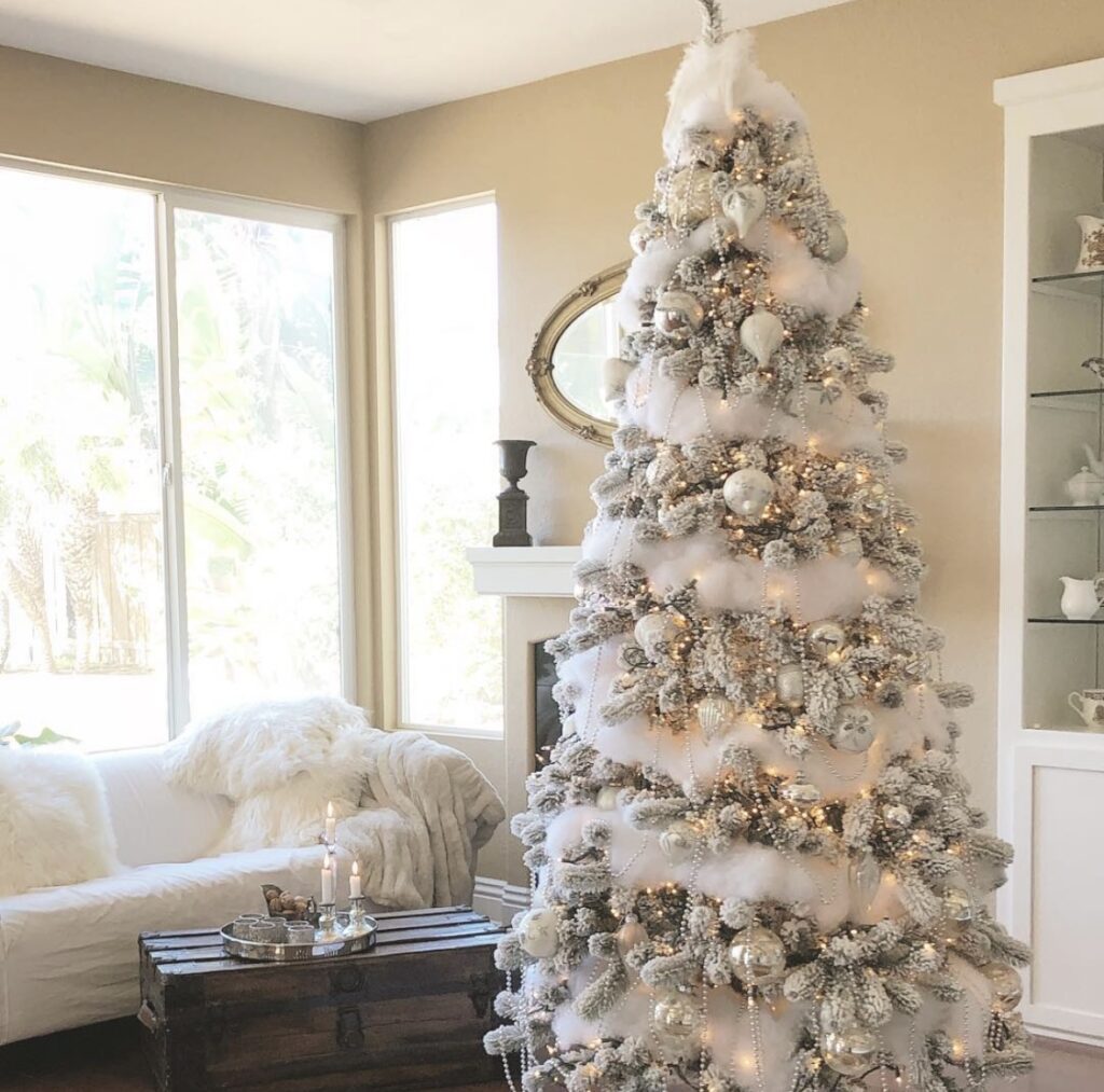 Winter wonderland Christmas tree styled in silver and white with layered ribbon, frosted picks, and warm twinkle lights.