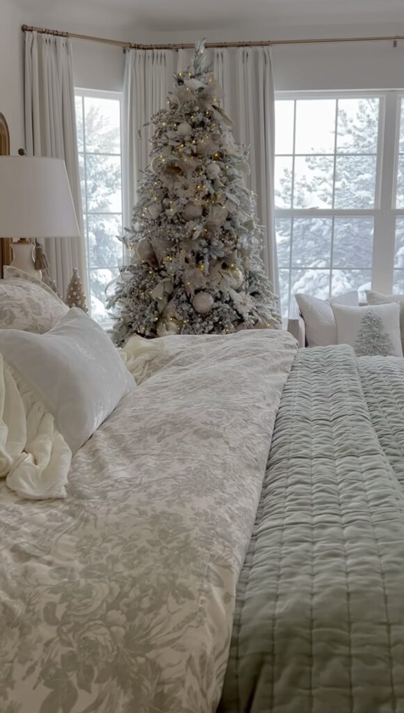 Cozy bedroom winter wonderland tree with neutral layers, snowy window backdrop, and soft twinkle lights.