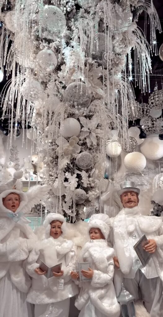 All-white upside down winter wonderland Christmas tree with icicles, vintage caroler figurines, and snow-soft lighting.