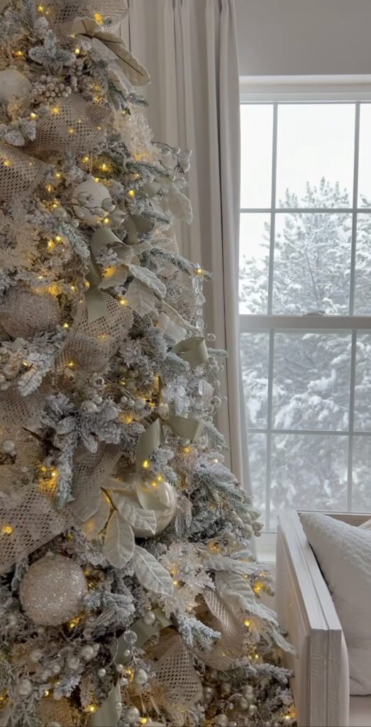 Winter wonderland tree close-up with ivory mesh ribbon, pearl accents, and warm white lights.