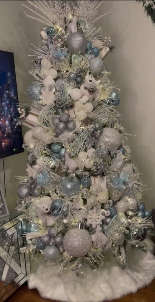 Winter wonderland tree detail with icy blue and silver sparkle ornaments and glittering ribbon.
