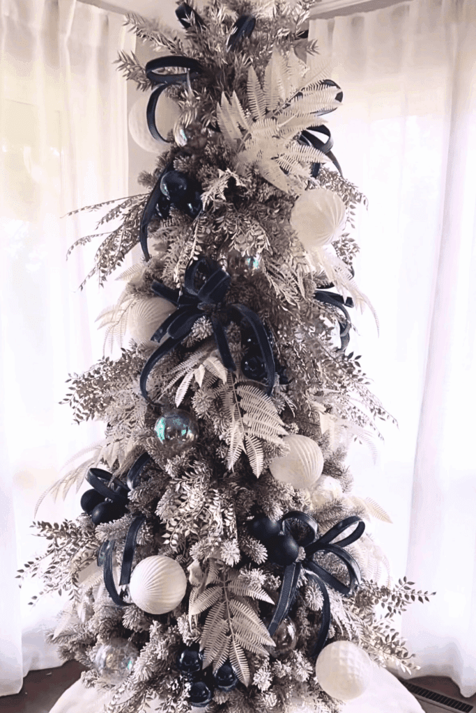 Winter wonderland slim tree dressed in silver ornaments, clear glass icicles, and snowy tips.