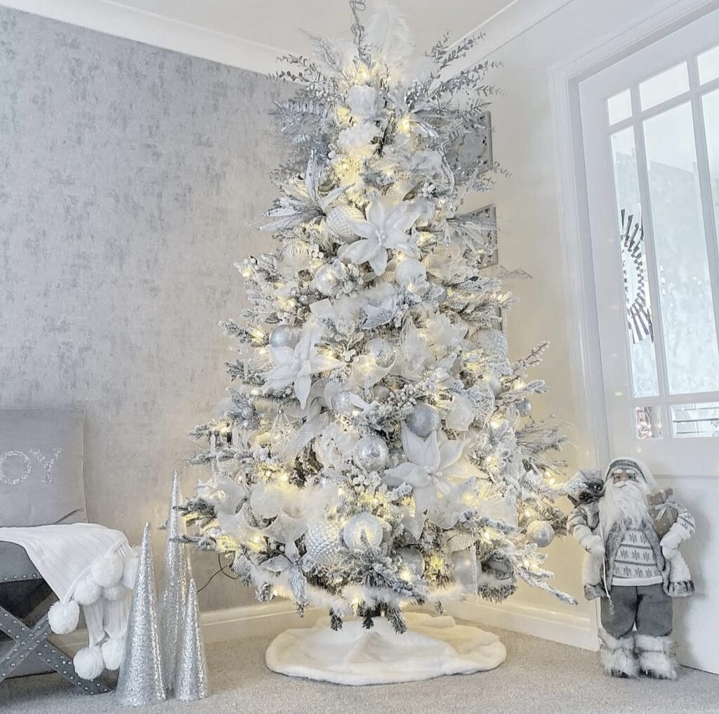Silver-and-white winter wonderland living room with a glam Christmas tree, mirrored ornaments, and warm twinkle lights.