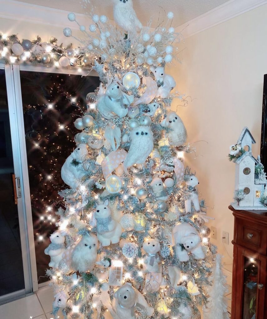 Winter wonderland tree detail with snowy owl and polar bear ornaments, icy branches, and glitter snowflakes.