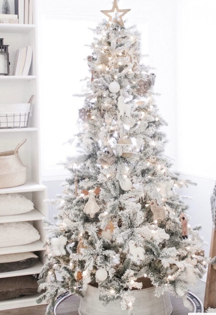 Winter wonderland flocked Christmas tree with snowy branches, metallic ornaments, and soft white lights.
