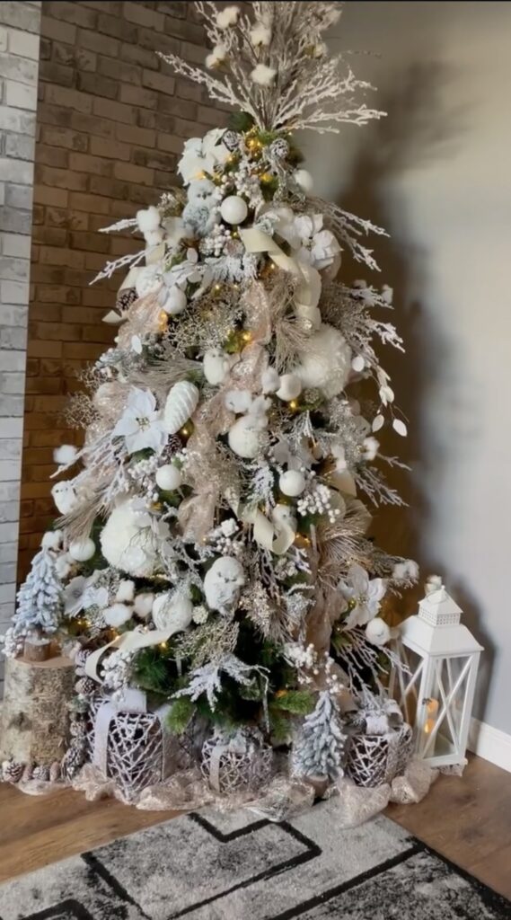 Silver and white winter wonderland Christmas tree with woven ribbon, star topper, and wicker tree collar.