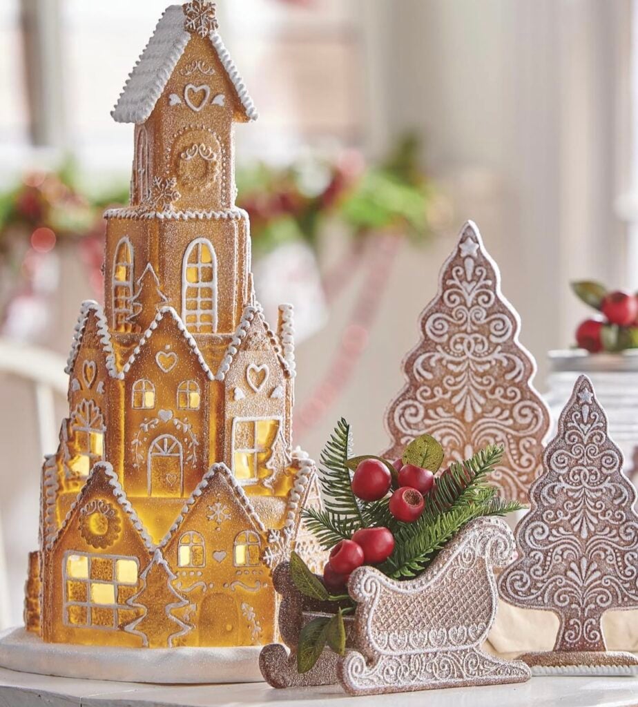 Gingerbread house vignette with nutcrackers, bottle brush trees, and warm white lights styled as cozy Christmas decor.