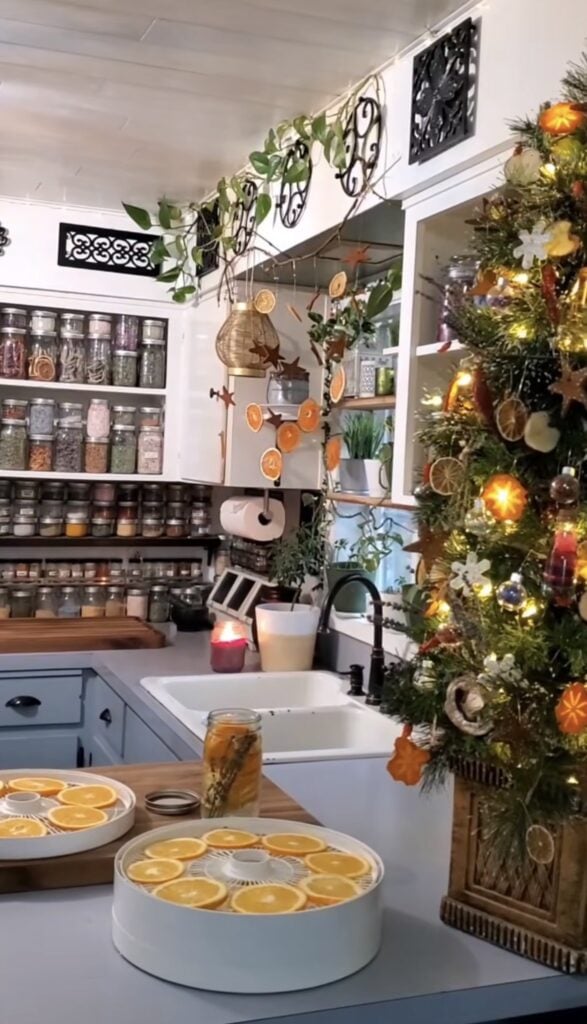 Cozy farmhouse kitchen decorated with evergreen garland, lanterns, candles, and Winter Solstice-inspired natural decor.