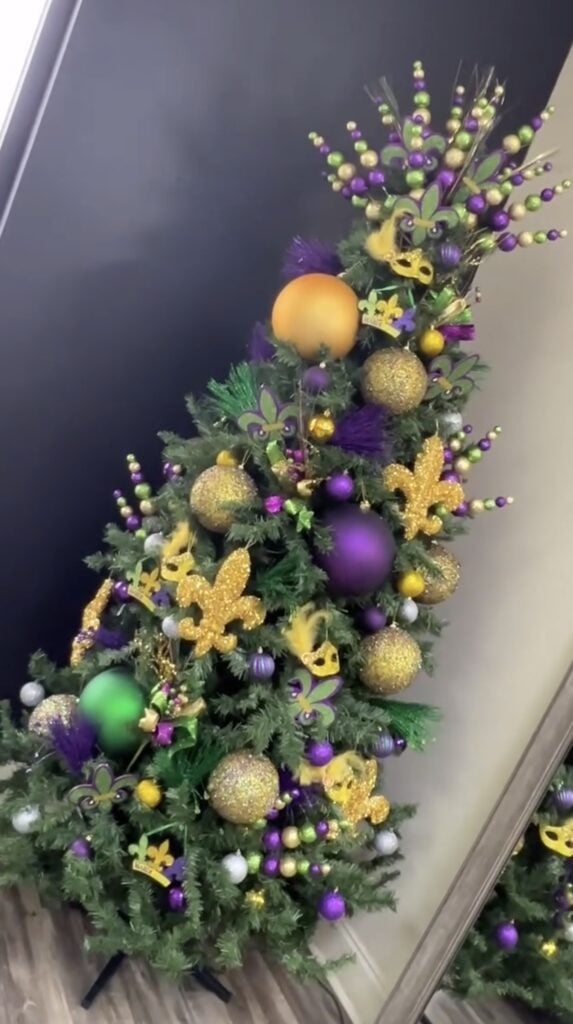 Mardi Gras tree with dramatic ornament clusters, bold ribbon, and playful parade-season details in purple, green, and gold.