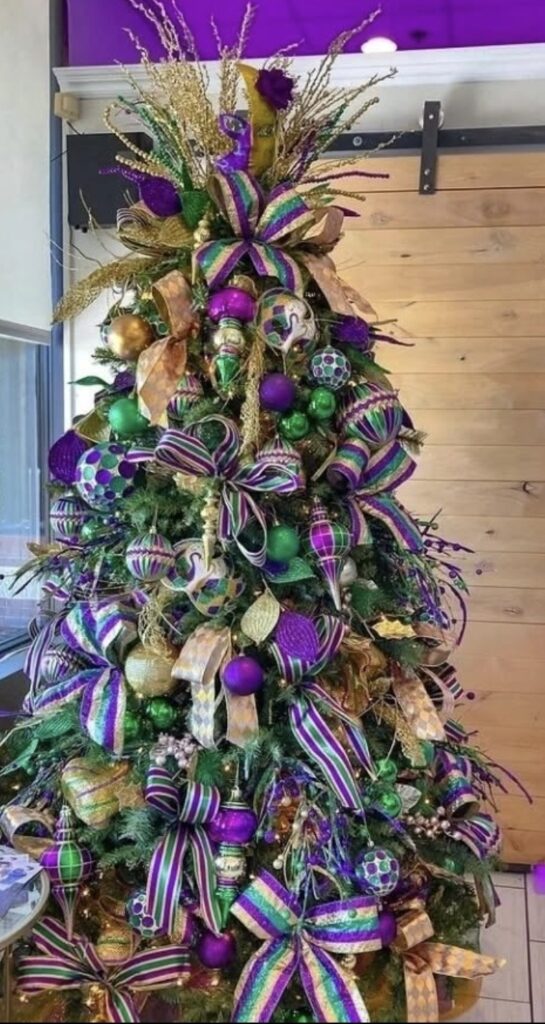 Mardi Gras Christmas tree decorated in purple, green, and gold with striped ribbon bows and glitter ornaments.