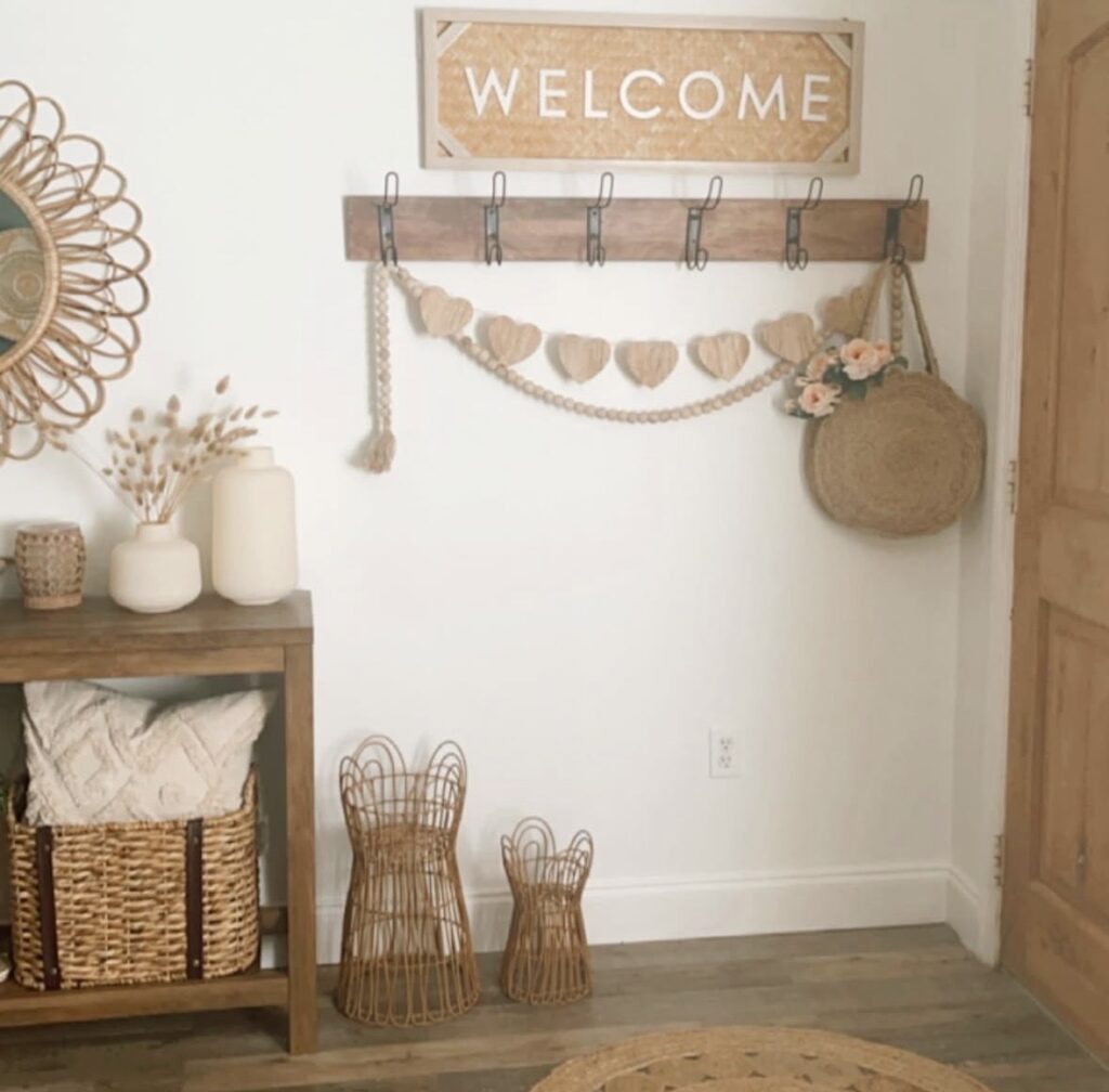 Neutral entryway decor with a “Welcome” sign, wooden heart garland, woven baskets, and warm wood tones in a cozy farmhouse space.