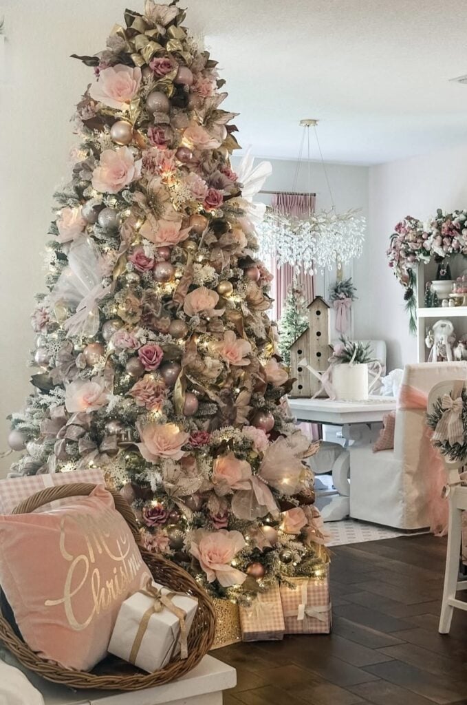 Elegant Christmas tree covered in blush pink roses, champagne gold ornaments, floral picks, and softly glowing lights.