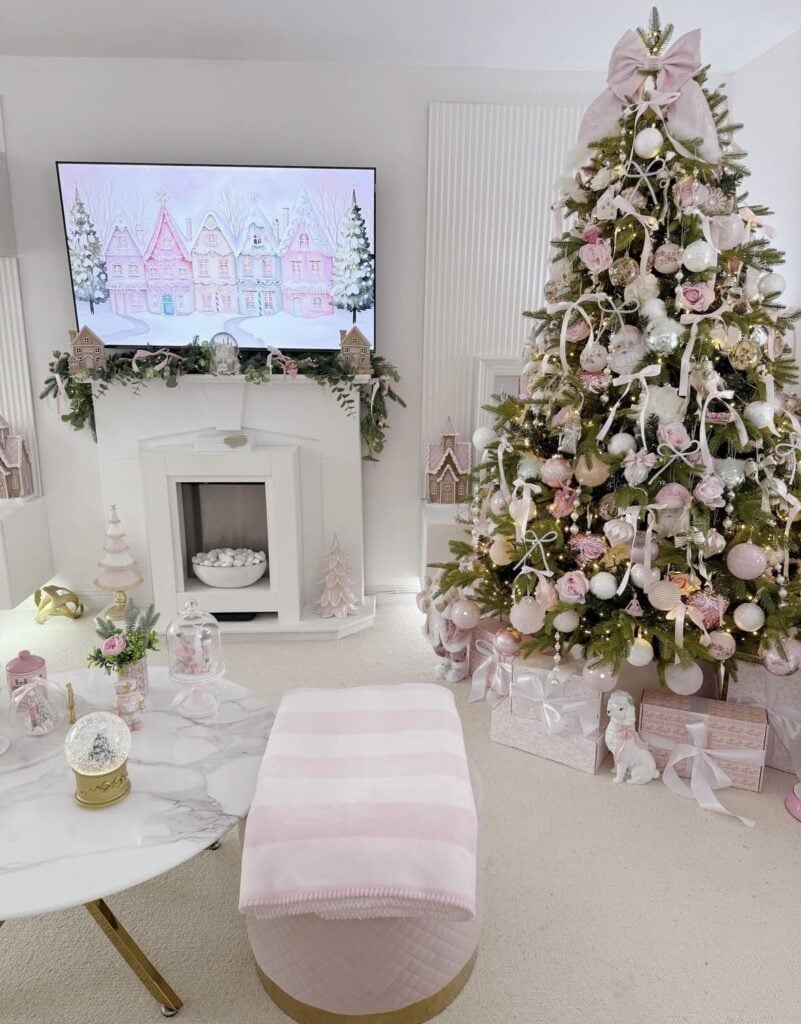 Full Christmas tree decorated with blush pink roses, bows, white ornaments, and warm lights in a soft pink and white living room.