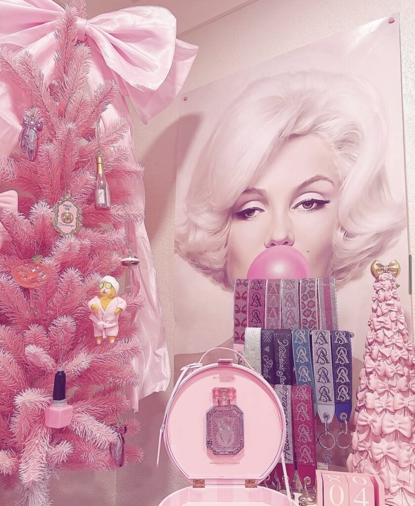 Flocked Christmas tree decorated with glittering pink ornaments and an oversized blush bow with long ribbon tails.