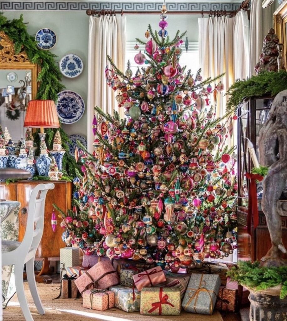 Maximalist Christmas tree packed with colorful vintage ornaments in pink, red, green, blue, and gold.
