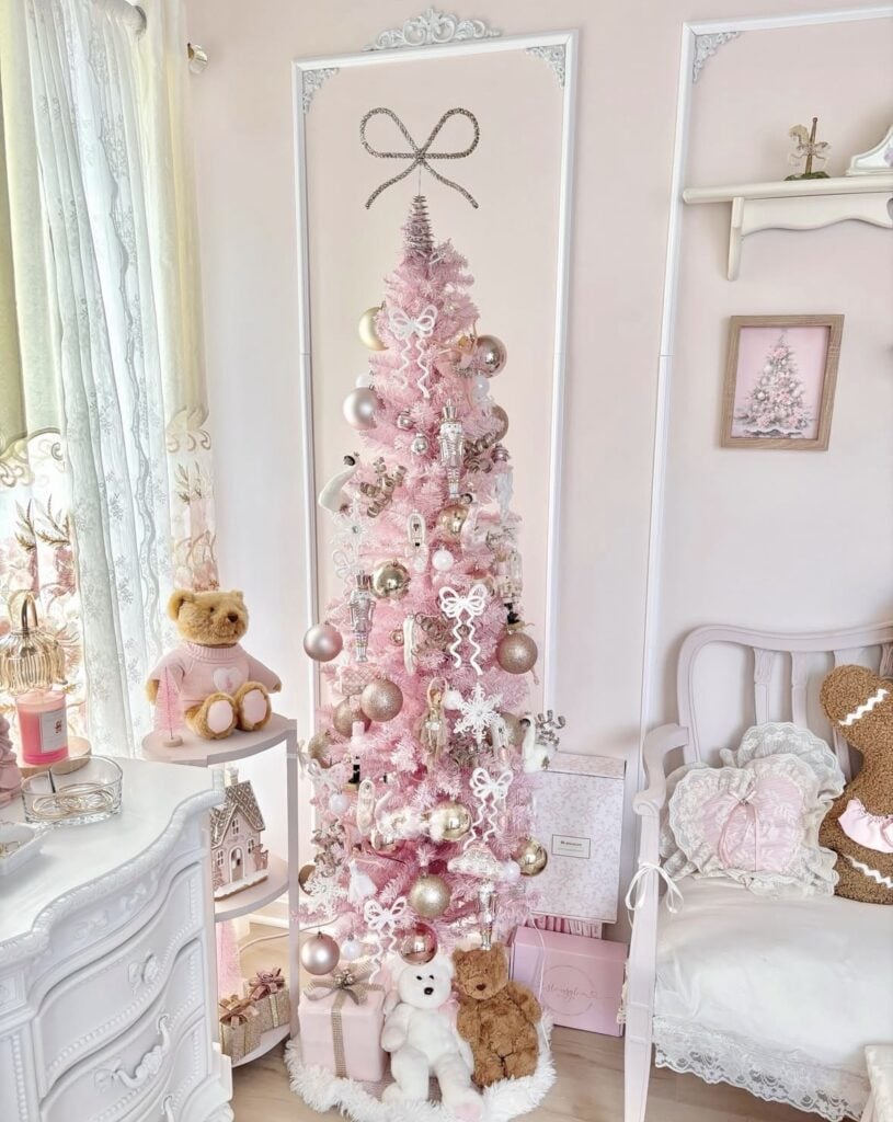 Slim pink Christmas tree decorated with white bows, gold and blush ornaments, snowflakes, and nutcracker decorations.