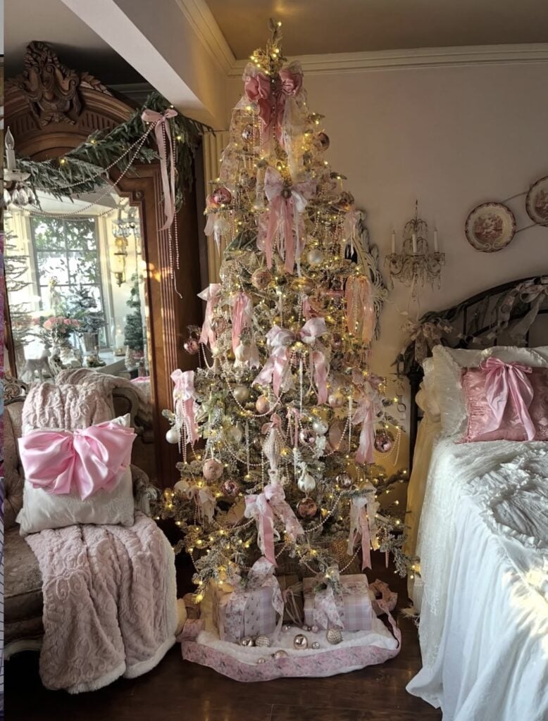 Romantic Christmas tree glowing with warm lights and decorated with pink satin bows, pearls, and vintage-style ornaments.
