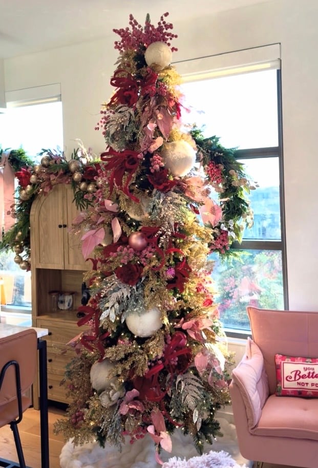 Christmas tree decorated with deep berry pink, blush, burgundy, gold, and white ornaments, ribbons, florals, and oversized textured baubles.