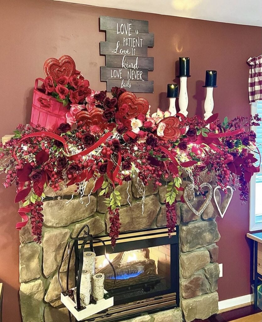 Stone fireplace mantle with red Valentine’s Day garland, heart picks, candles, and love quote sign.