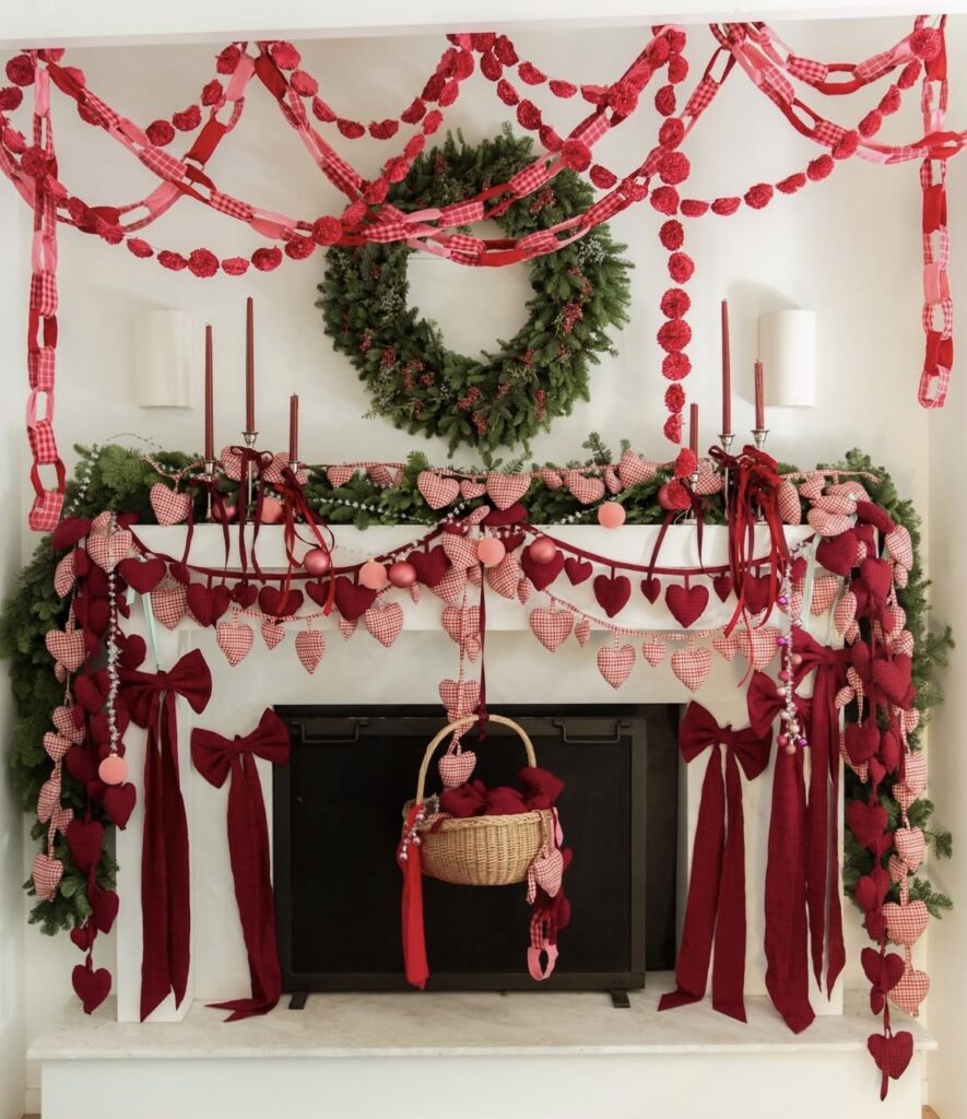 Romantic Valentine mantel covered in red heart garlands, bows, greenery, and hanging heart decor.