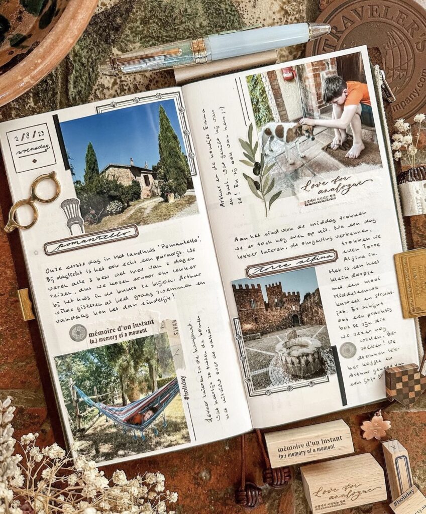 Open travel journal with photo-heavy pages showing countryside scenes, a child with a dog, castle photo, and handwritten journaling on a rustic tabletop.