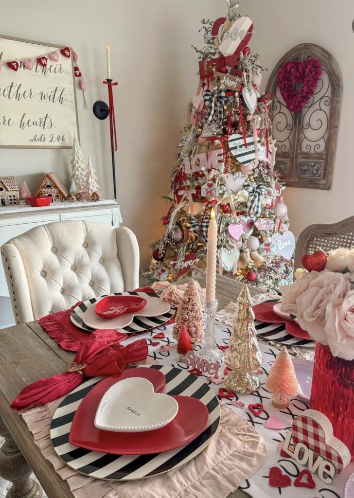 Valentines Day tree styled with red and pink ornaments, heart garlands, and coordinating decor on a table, credit blessednesting.