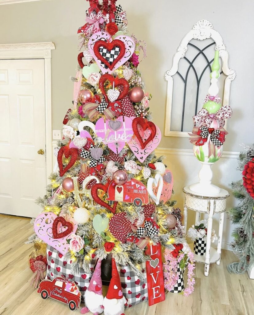 Whimsical Valentines Day tree with pink and red decorations, heart garlands, and layered ribbon, credit oliviasromantichome.
