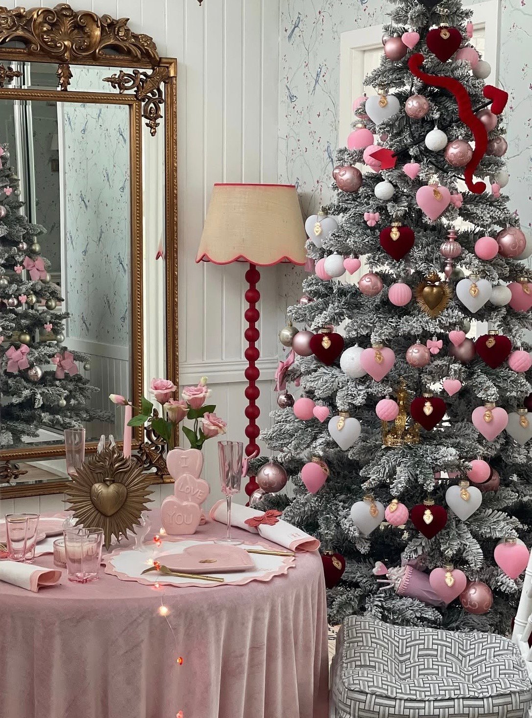 Traditional Valentines Day tree with red ribbon, heart ornaments, and coordinating decor around the base, credit hamptonsdiaries.