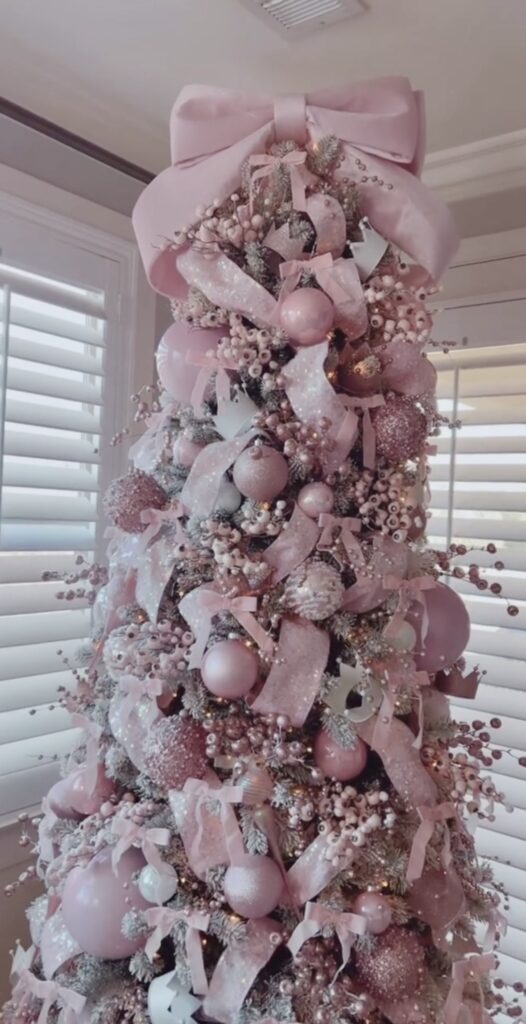 Elegant light pink Valentines Day tree styled with pink and ornaments and bow touches in a warm living room, credit corrie9.
