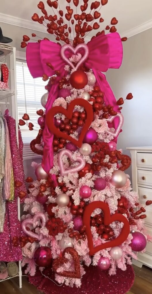 Huge Bright pink bow on Valentines Day tree with candy hearts, pink ribbon, and playful decorations in a bright room, credit savannahhhhleem.