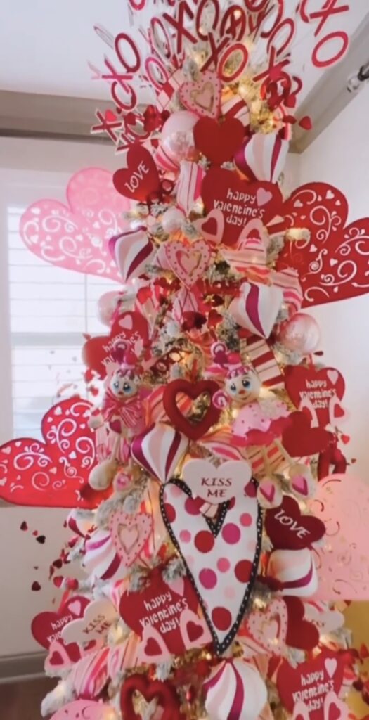 Valentines Day tree with bright red and pink heart ornaments and xoxo topper styled in a warm living space, credit corrie9.