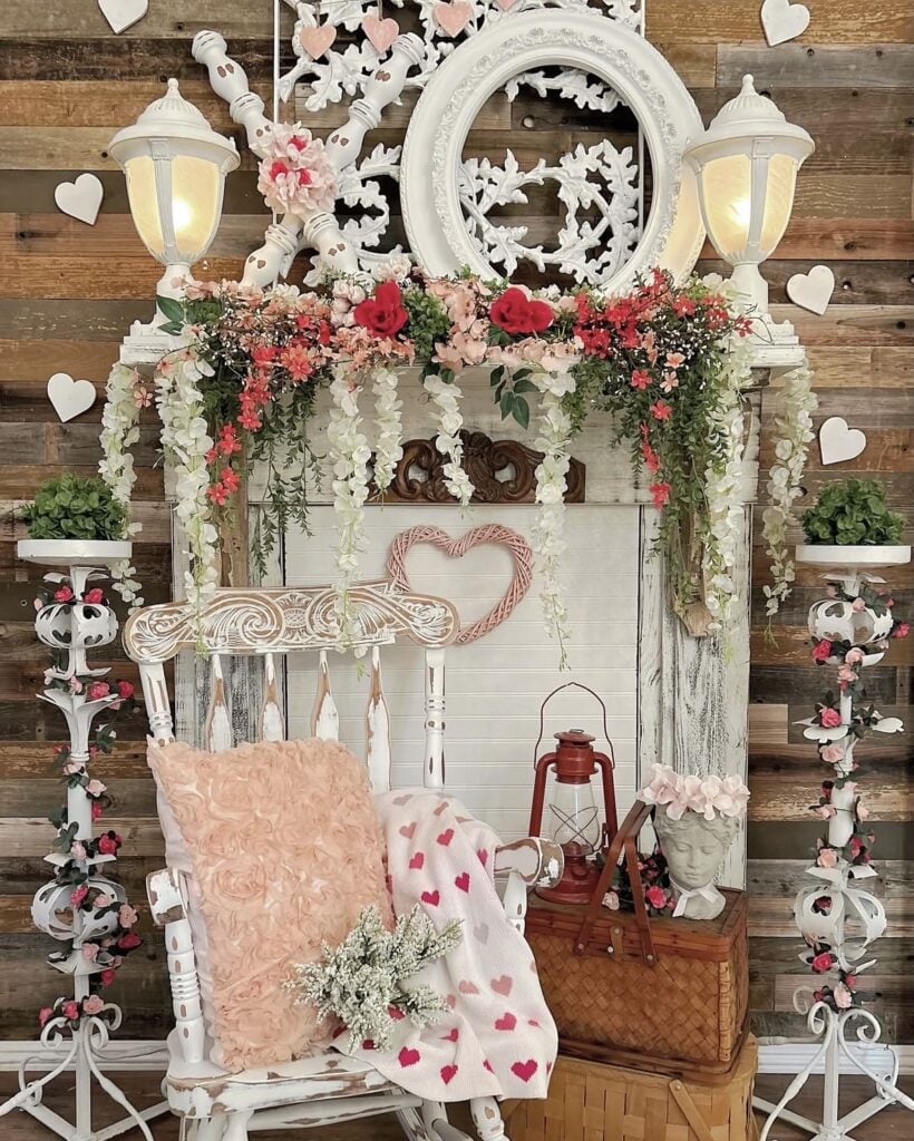 Rustic Valentine mantel decor with white lantern lights, blush and red flowers, heart accents, and a cozy chair vignette.